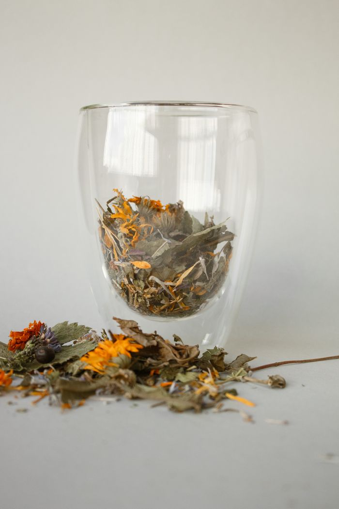 Glass filled with aromatic dried leaves for herbal tea on a studio background.